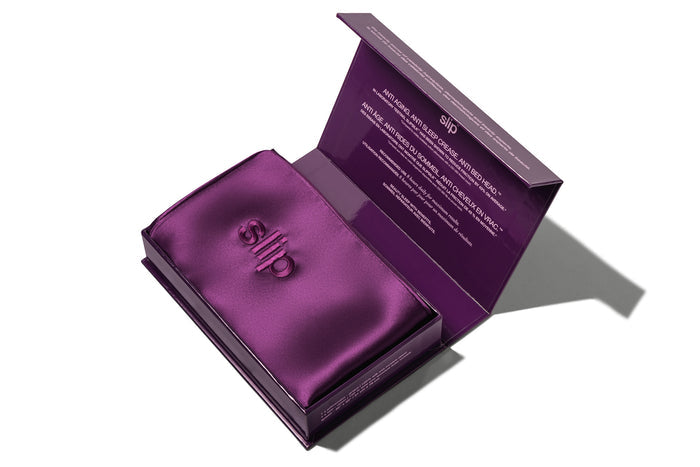 A dark purple slip silk queen pillowcase in open branded packaging on a white background.