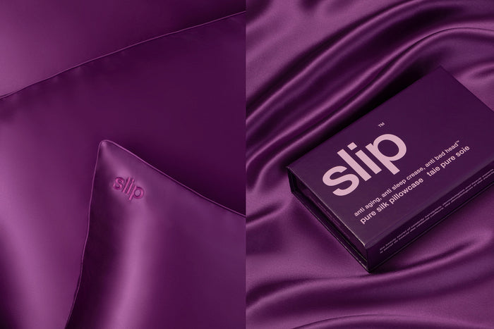 A dark purple slip silk queen pillowcase in open branded packaging resting on dark purple slip silk queen pillowcases
