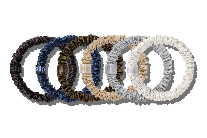 Slip silk skinny scrunchies in white, silver, blonde, navy, dark brown, and black on a white background.