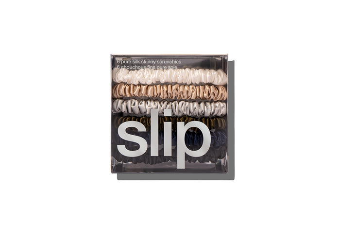 Slip silk skinny scrunchies in white, silver, blonde, navy, dark brown, and black displayed in branded packaging on a white background.
