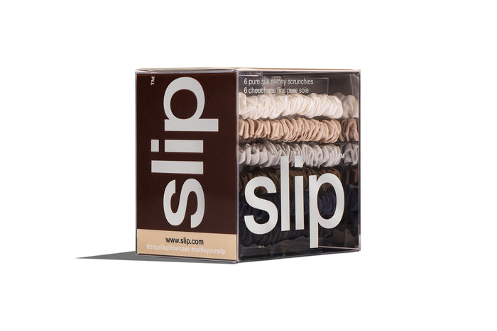 Slip silk skinny scrunchies in white, silver, blonde, navy, dark brown, and black displayed in branded packaging on a white background.