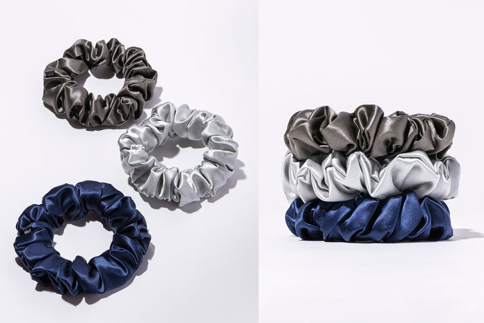 A flatlay and stacked shot of slip silk large scrunchies in navy, silver, and charcoal, on a white background.