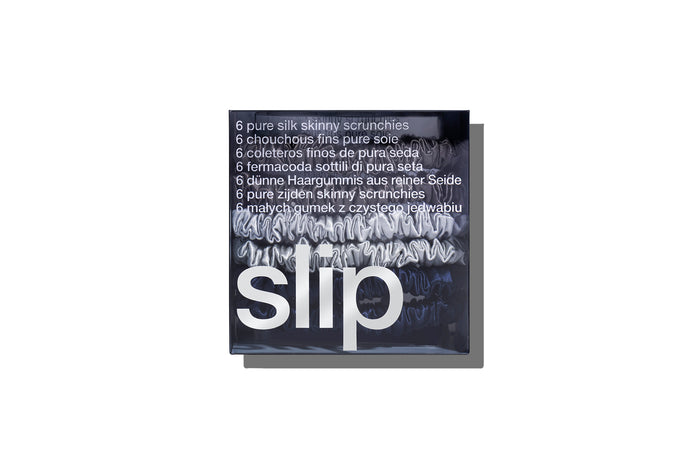 A set of six slip silk skinny scrunchies in navy, silver, and charcoal, displayed in branded packaging on a white background.