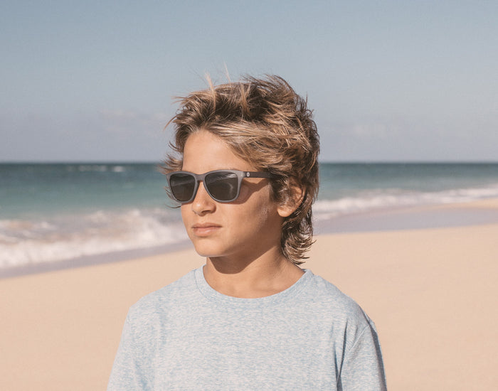 STORY boy on the beach in the wind wearing sunski mini headland sunglasses