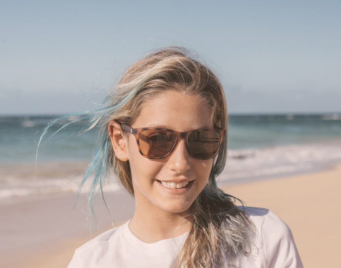 STORY girl on the beach wearing sunski mini madrona sunglasses