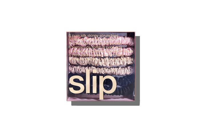 A set of six slip silk skinny scrunchies in pink, caramel, and black in a branded box on a white background.