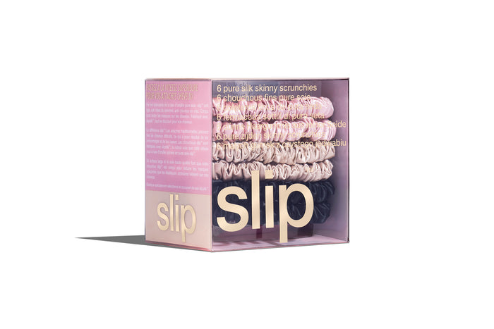 A set of six slip silk skinny scrunchies in pink, caramel, and black in a branded box on a white background.