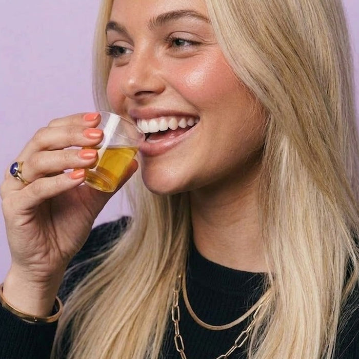 Lifestyle: profile view of woman drinking the Maniac Nails Nail Vitamin Shot.