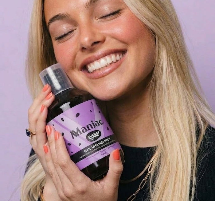 Lifestyle: woman holding the Maniac Nails Nail Vitamin Shot bottle. Liquid nail vitamins for daily use.