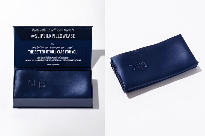 Flatlay of folded navy slip silk king pillowcase and open branded packaging on a white background.