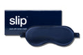 A navy slip silk sleep mask displayed with branded packaging on a white background.