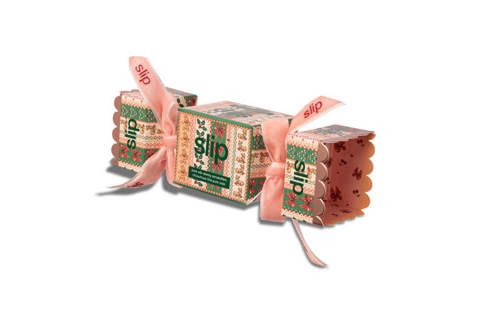 Slip Scrunchie cracker packaging with a pink ribbon, each printed with the word 'slip' and a festive pattern, on a plain white background.