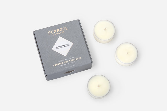 Set of Norwegian Woods scented tealight candles next to premium gray box with Penrose Candles branding.