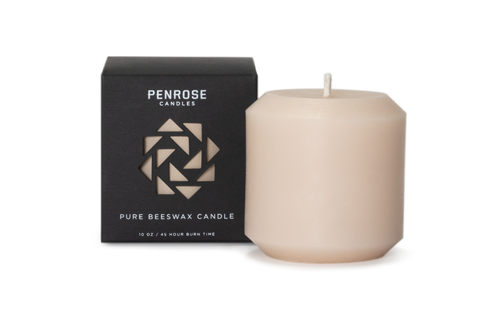 Nude beige beeswax pillar candle next to black Penrose Candles packaging box with geometric logo design
