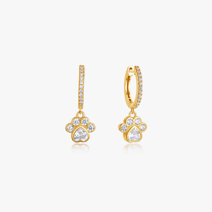 Pave Paw Huggies from the Pawsitive Change Collection: Gold-tone hoops with paw-print charms, featuring heart-shaped and round crystals, perfect for sensitive skin.