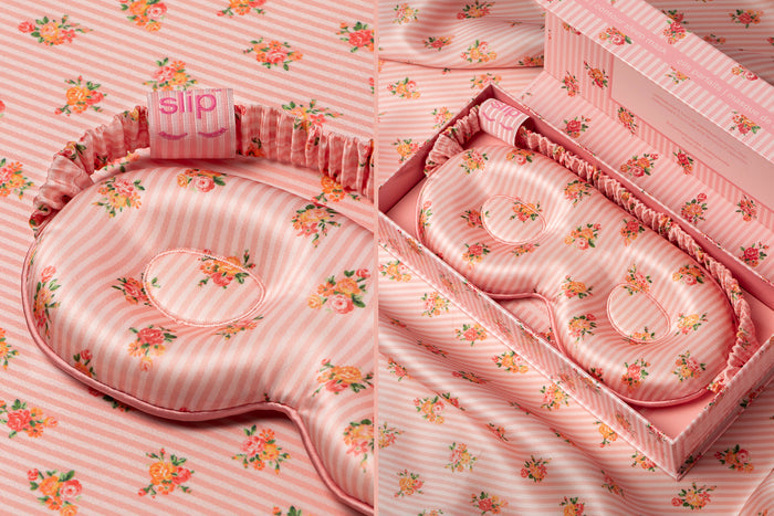 A floral pink stripe slip silk contour sleep mask, designed to protect delicate eyelash extensions, in open branded packaging on a matching pattern silk background.