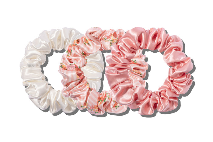 Set of pink, floral pattern and white large slip silk scrunchies on a white background.