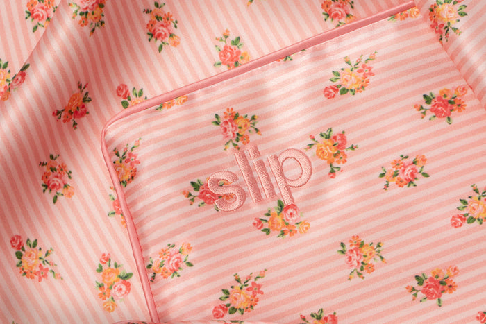 Embroidered pink slip logo on a floral pink and white stripe silk queen pillowcase.