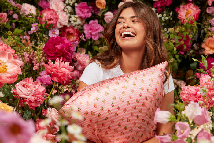 Woman holding a floral pink and white stripe slip silk queen pillowcase
