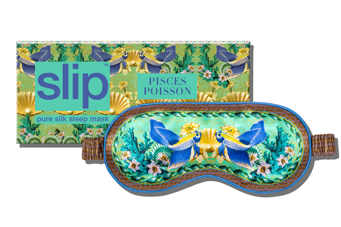 A floral and fish patterned slip silk sleep mask for Pisces star sign with blue, green, and brown colors. Displayed alongside branded packaging on a white background.
