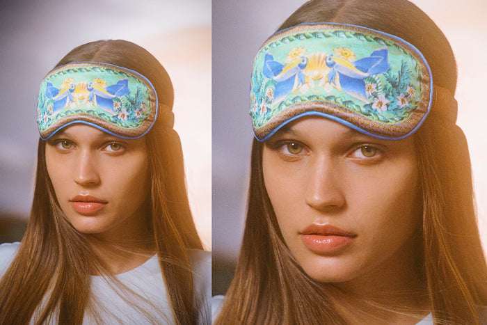 A woman wearing a floral and fish patterned slip silk sleep mask for Pisces star sign with blue, green, and brown colors.