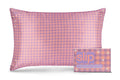 A slip silk queen pillowcase with a pink and purple checkered pattern and embroidered daisies, displayed alongside its slip packaging on a white background.