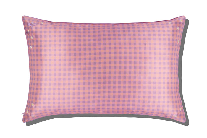 A slip silk queen pillowcase with a pink and purple checkered pattern and embroidered daisies on a white background.