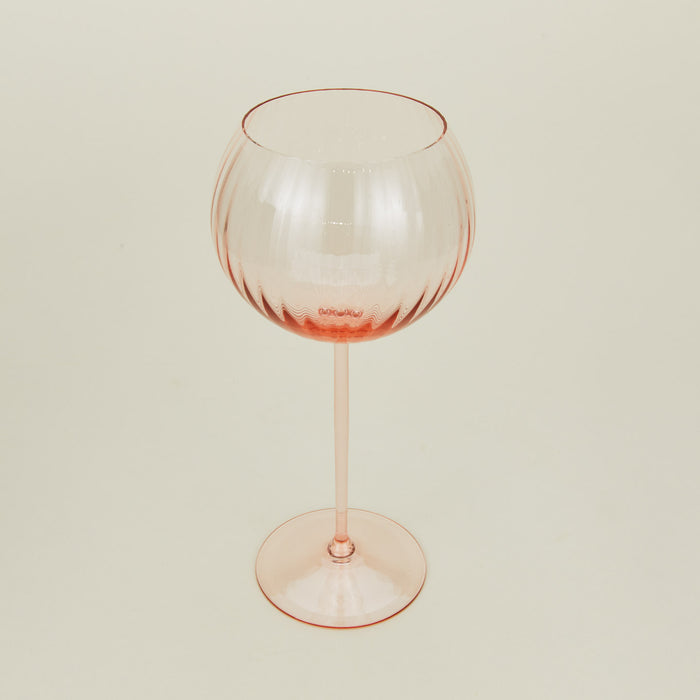 Three-quarter angle of ribbed blush wine glass.