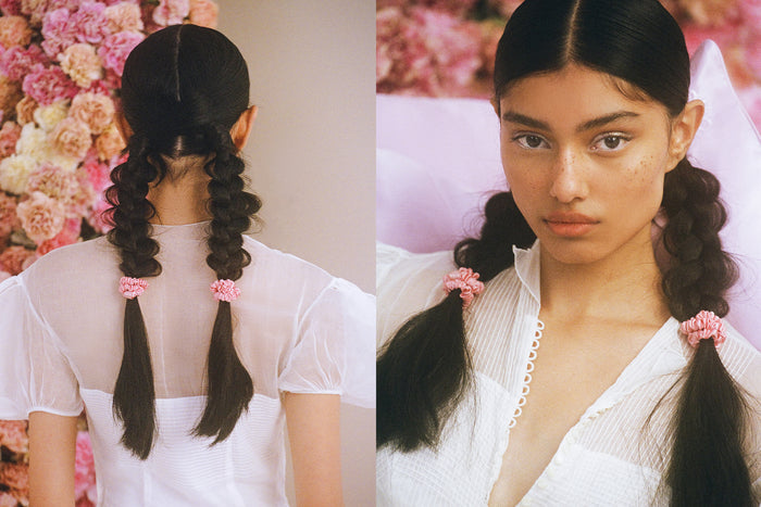 Woman with hair in braids with blush pink silk skinny scrunchies.