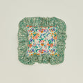 A ruffled floral cushion with a fern pattern.