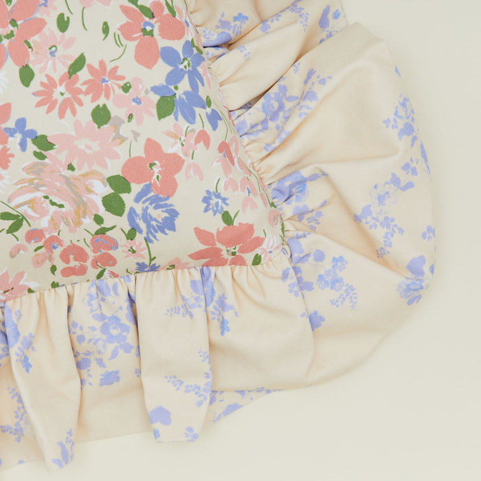 A close up of a ruffled floral cushion with a rose pattern.