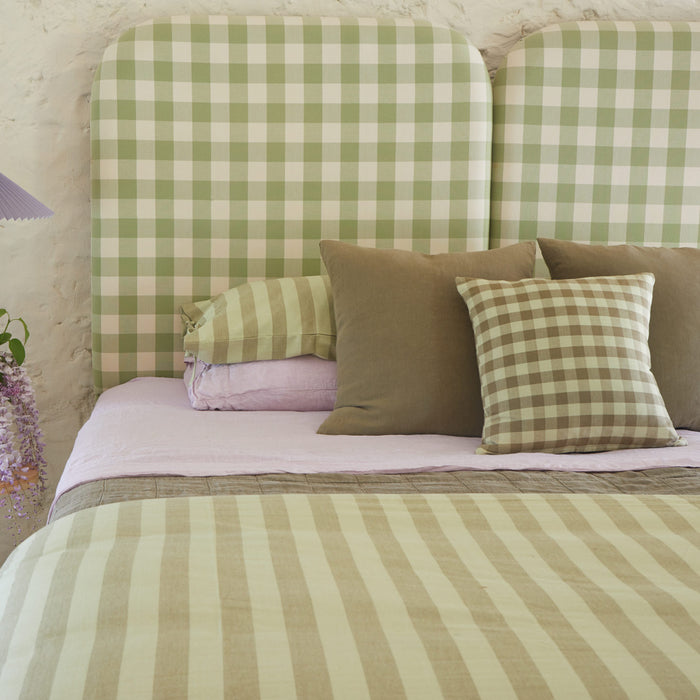 Bed with green and lilac bedding in stripes and gingham.