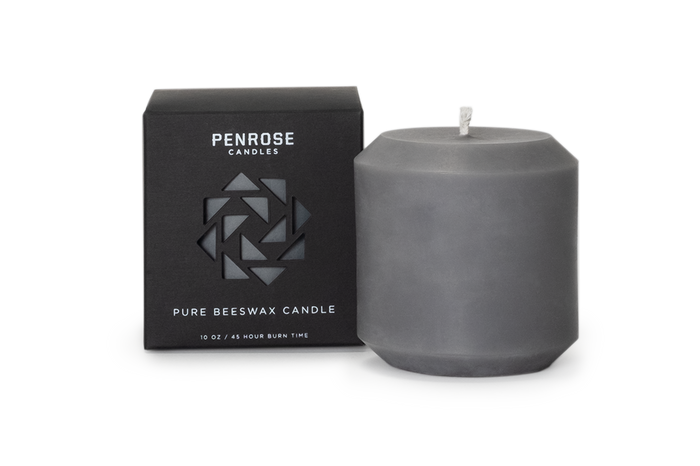 Slate gray beeswax pillar candle next to black Penrose Candles packaging box with geometric logo design