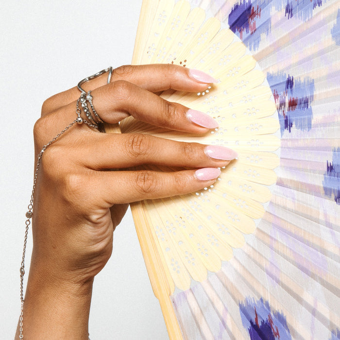 Hand with Sugar Shimmer nail stickers by Maniac Nails holding a paper fan