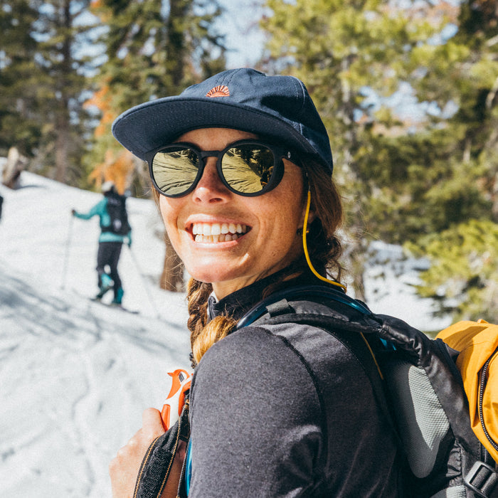 Person hiking in a snowy landscape with trees and another person in the background.