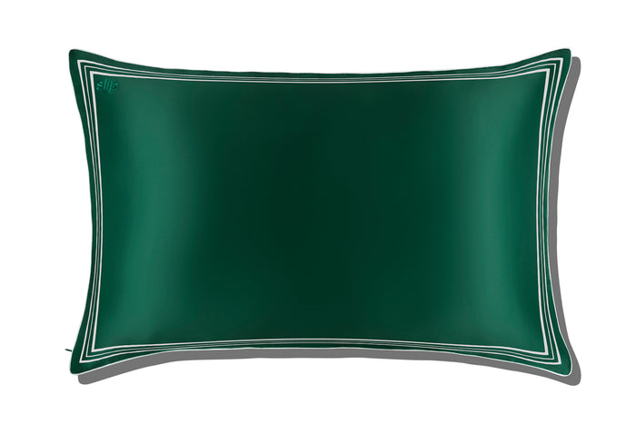 Green silk pillowcase with white decorative trim and piping on a white background