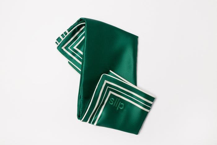 Green silk pillowcase with white stripes and slip embroidery on a light grey background