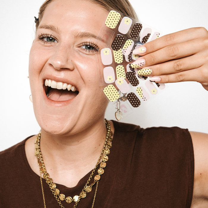 Model holding Toast and Honey gel nail sticker sheets by Maniac Nails