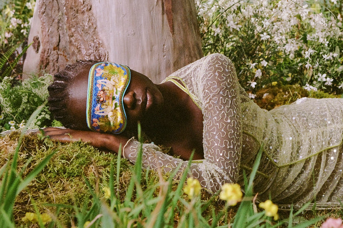 Model wearing Virgo silk sleep mask, sleeping in a forest setting.
