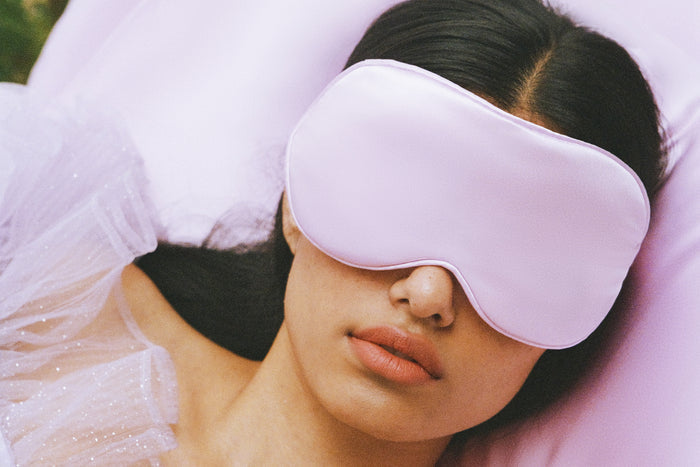 A woman wearing a purple slip silk contour sleep mask, designed for eyelash extension wearers.