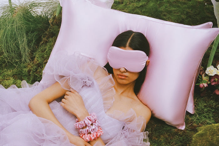 A woman wearing a purple slip silk contour sleep mask, designed for eyelash extension wearers.