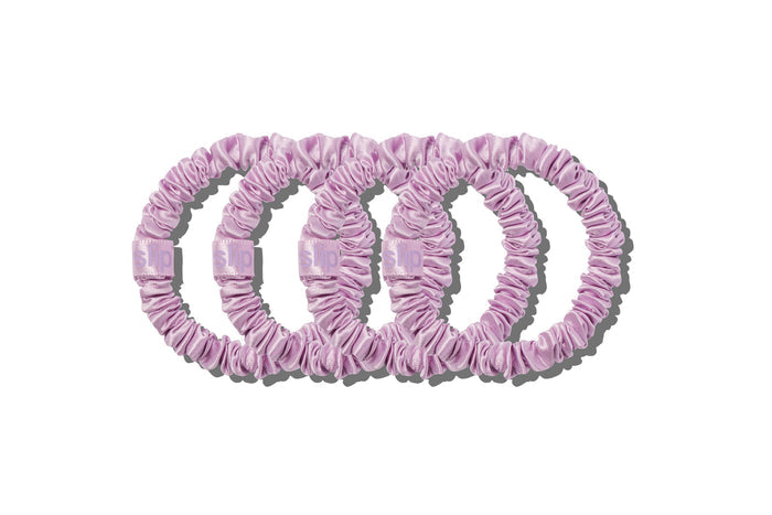 Four lilac silk skinny scrunchies on a white background