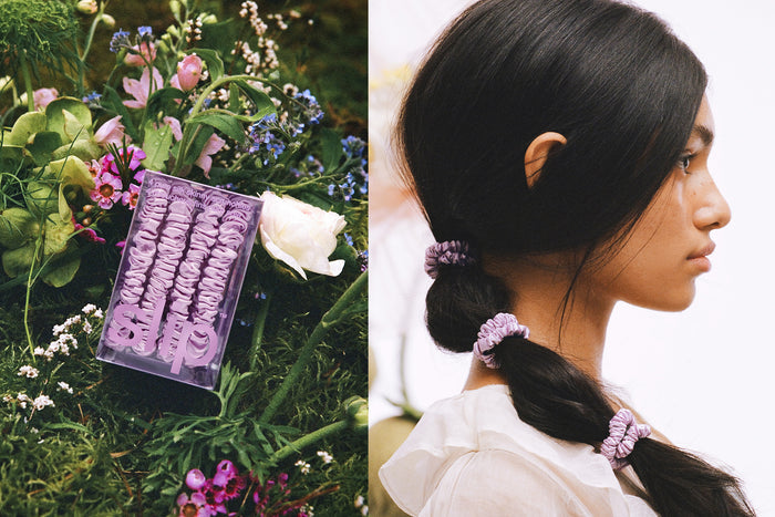 Slip silk lilac skinny scrunchies in brand packaging in a garden bed. Woman with styled ponytail with lilac slip silk skinny scrunchies.