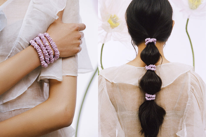 Set of four lilac slip silk skinny scrunchies on a wrist. Woman with styled ponytail with lilac slip silk skinny scrunchies .