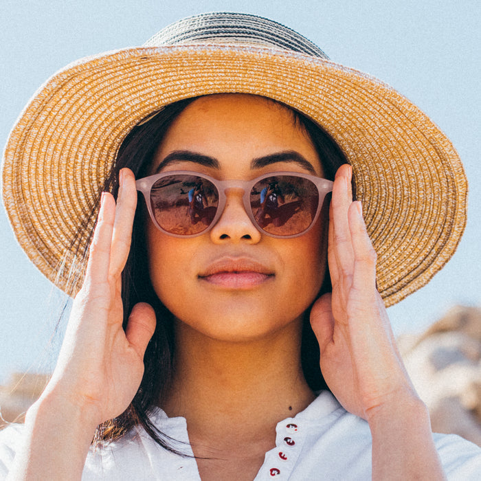 Woman wearing a straw hat and sunglasses with a blurred background